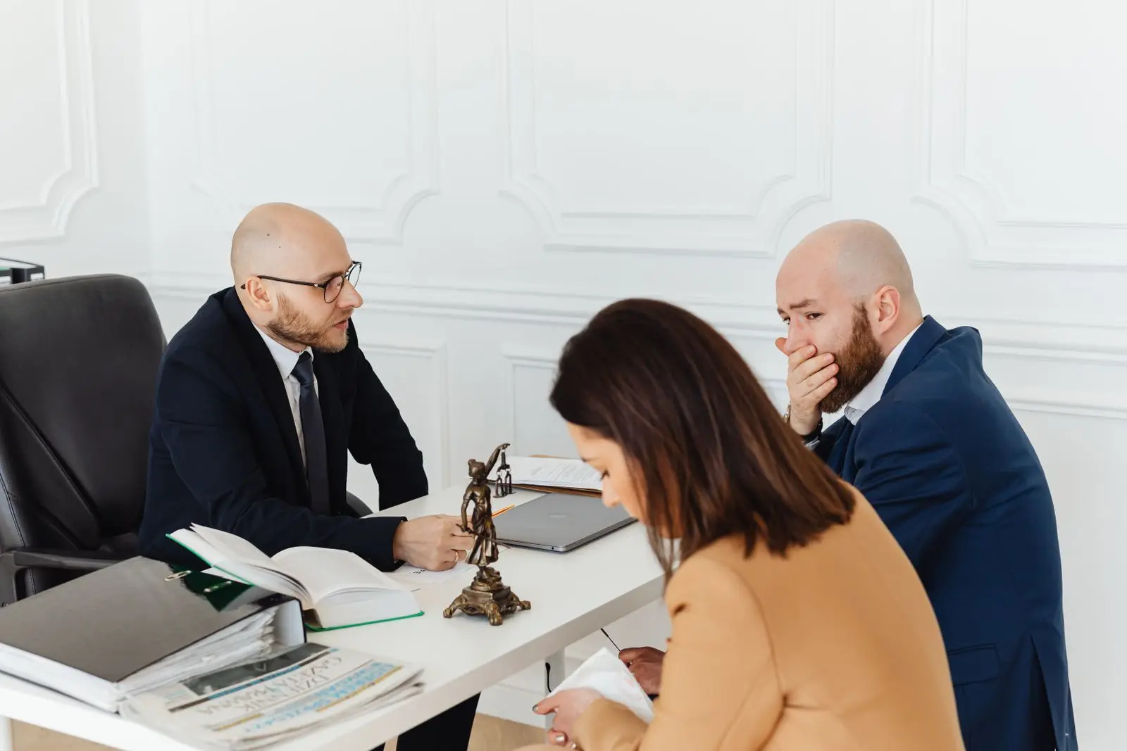 Dois advogados conversando com uma cliente em volta da mesa do escritório