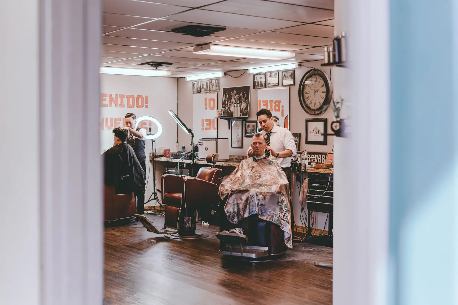 Barbeiros atendendo clientes nas cadeiras da barbearia
